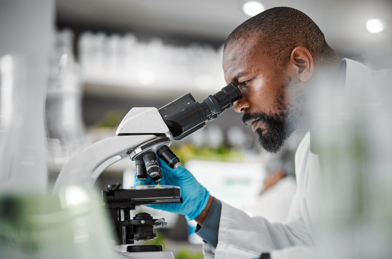 Scientist using a microscope in a biotech laboratory, conducting detailed life science research focused on cellular analysis and discovery within the life sciences field.